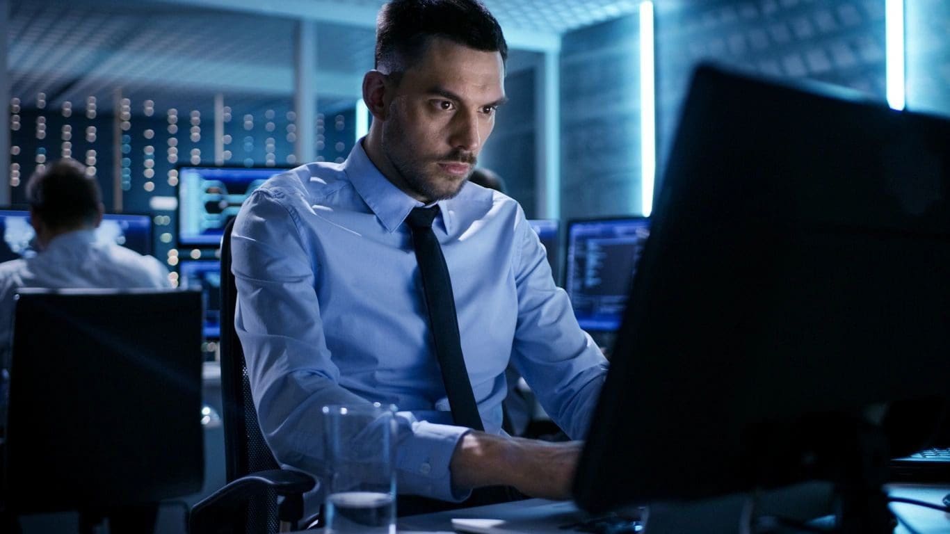 A man sitting at his desk looking at the computer screen.